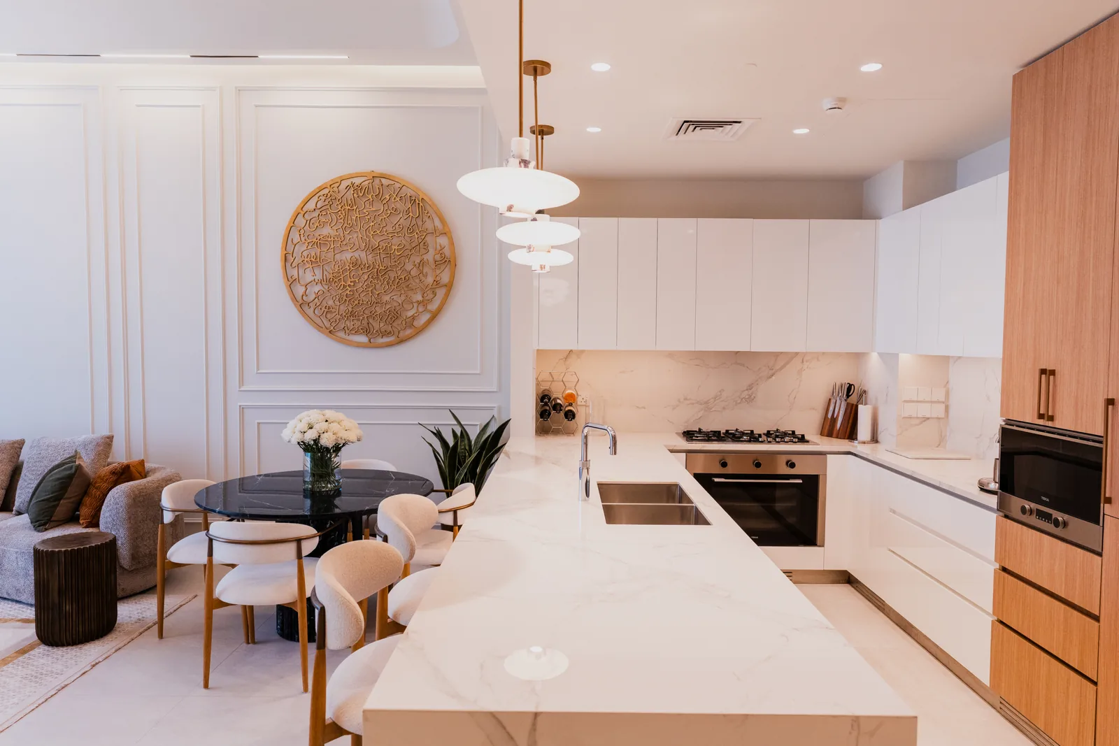 Ellington House kitchen with white marble island and wood tall units by an interior designer in Dubai